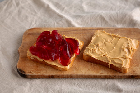 Homemade Peanut Butter and Jelly Sandwich on a rustic wooden board, side view.