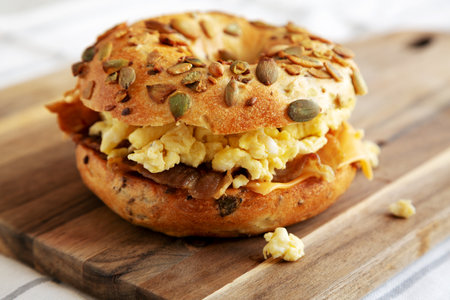 Homemade Bacon, Egg & Cheese Bagel Breakfast Sandwich on a wooden board, side view.の写真素材