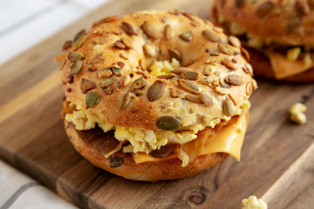 Homemade Bacon, Egg & Cheese Bagel Breakfast Sandwich on a wooden board, side view. copyspace.の写真素材
