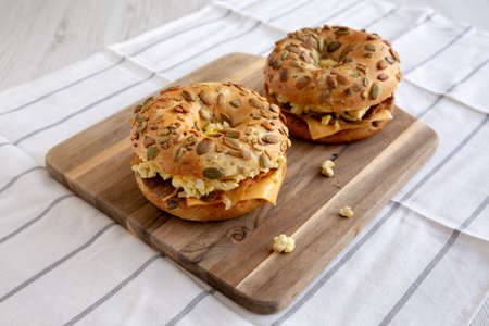 Homemade Bacon, Egg & Cheese Bagel Breakfast Sandwich on a wooden board, side view.の写真素材