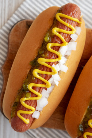 Char Grilled Hot Dog with Mustard, Relish and Onion on a rustic wooden board, top view.の写真素材