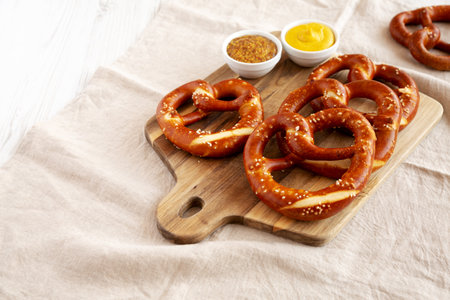 Homemade Soft Bavarian Pretzels with Mustard on a wooden board, side view. Copy space.の写真素材