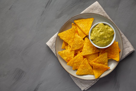 Homemade Guacamole with Tortilla Chips on a Plate, top view. Copy space.