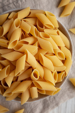 Raw Organic Dry Pennoni Pasta in a Bowl, top view. Close-up.