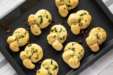 Homemade Garlic Knots with Parsley on a Baking Tray, top view.