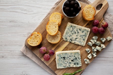 Organic Blue Cheese with Grapes and Olives on a Wooden Board, top view. Copy space.