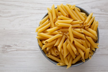Raw Organic Dry Penne Pasta in a Bowl, top view. Overhead, flat lay, from above. Copy space.の写真素材