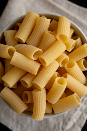 Dry Rigatoni Pasta in a Bowl on a black background, top view.の写真素材