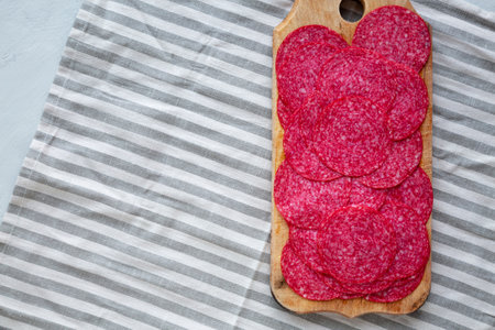 Sliced Spanish Salami Extra on a wooden board, top view. Flat lay, overhead, from above. Copy space.の写真素材