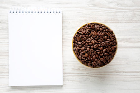 Organic Roasted Coffee Beans in a Bowl, Blank Notepad, top view.の写真素材
