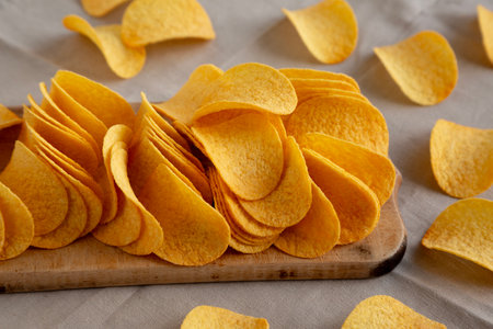 Bacon flavored potato chips on a wooden board, side view.