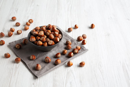Organic Raw Hazelnuts in a Bowl, side view. Copy space.