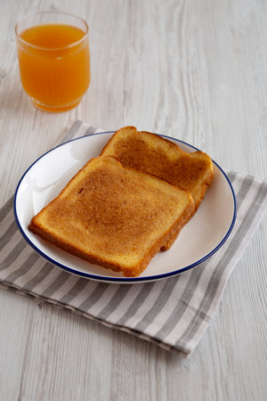 Homemade American Cinnamon Toast with Butter and Orange Juice, side view.