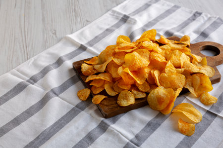 Homemade Flavored Cheese Potato Chips on a Wooden Board, side view. Copy space.