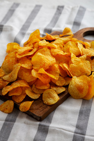 Homemade Flavored Cheese Potato Chips on a Wooden Board, side view.