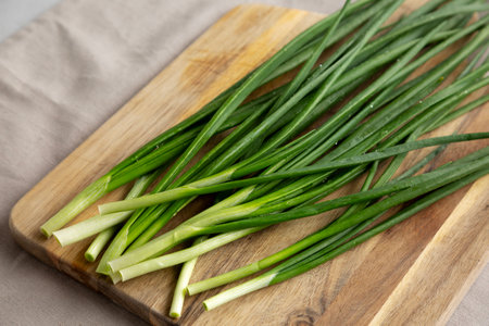 Raw Green Chives on a Wooden Board, side view.