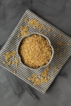 Raw Organic Orzo Pasta in a Bowl, top view. From above, overhead, flat lay.
