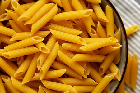 Homemade Raw Dry Penne Pasta in a Bowl, top view. Close-up.