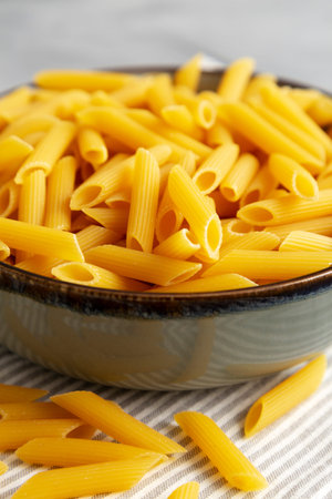 Homemade Raw Dry Penne Pasta in a Bowl, side view. Close-up.