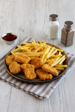 Fried Chicken Nuggets and French Fries with Barbecue Sauce, side view.
