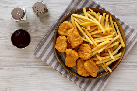 Fried Chicken Nuggets and French Fries with Barbecue Sauce, top view.