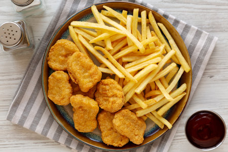 Fried Chicken Nuggets and French Fries with Barbecue Sauce, top view.