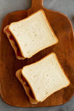 Homemade Peanut Butter and Jelly Sandwich on a Wooden Board, top view.