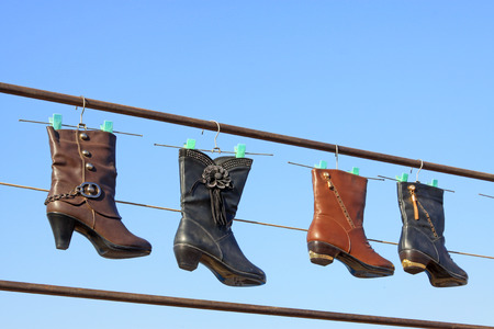 women's boots hanging in the blue sky, closeup of photoの写真素材