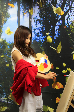 FENGNAN CITY - MARCH 30: A white skirt female model adjustment color with palette, March 30, 2014, Fengnan city, hebei province, China. 
のeditorial素材