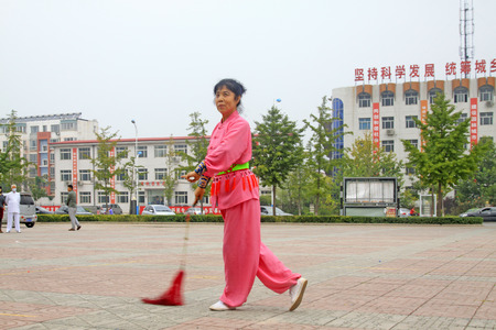 LUANNAN COUNTY - SEPTEMBER 20: Old woman practicing martial arts in a square on September 20, 2014, Luannan county, Hebei Province, Chinaのeditorial素材