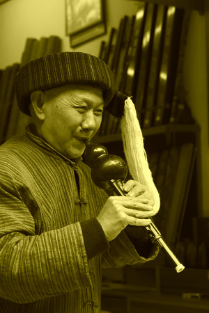 Phoenix County, April 15: Old man playing bottle gourd silk on April 15, 2012, Phoenix County, Hunan Province, Chinaのeditorial素材