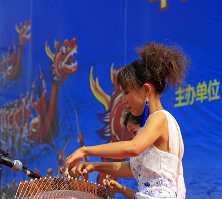 LUANNAN COUNTY - AUGUST 10: Playing the guzheng in the open air show, on august 10, 2014, Luannan County, Hebei Province, China.のeditorial素材