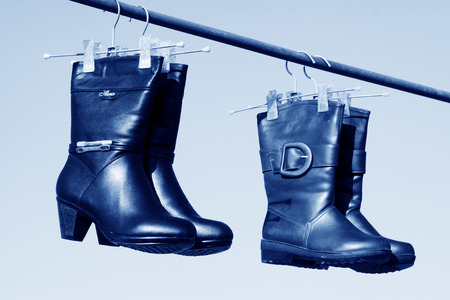 women's boots hanging in the blue sky, closeup of photoの写真素材