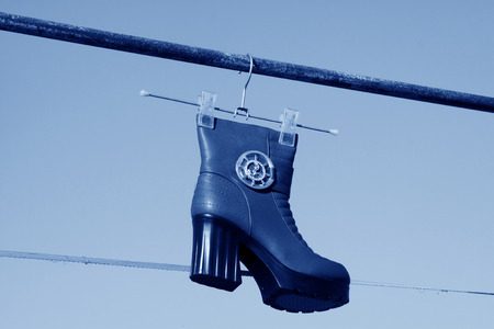 women's boots hanging in the blue sky, closeup of photoの写真素材