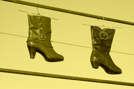 women's boots hanging in the blue sky, closeup of photoの写真素材