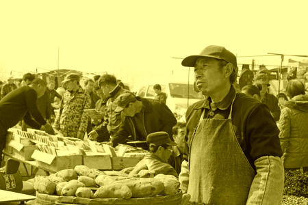 LUANNAN COUNTY - MARCH 23: Man selling baked sweet potatoes at the market on march 23, 2014, luannan county, hebei province, chinaのeditorial素材