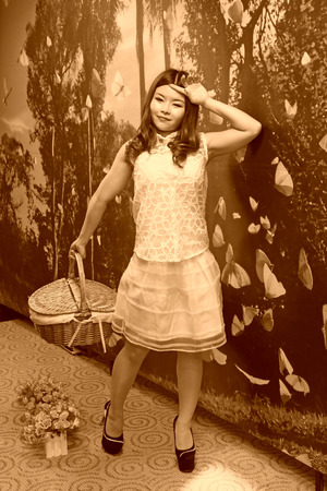 FENGNAN CITY - MARCH 30: A white skirt female model carrying basket standing, March 30, 2014, Fengnan city, hebei province, China.のeditorial素材