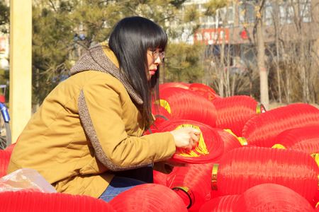 LUANNAN COUNTY - MARCH 5: On the Lantern Festival Day, A lady was busy installing red lanterns in a park, March 5, 2015, luannan county, hebei province, Chinaのeditorial素材