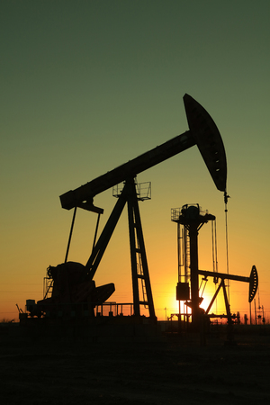 Beam balanced pumping unit under the setting sun in oilfieldのeditorial素材