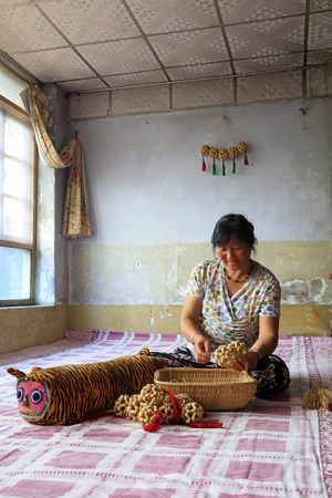 Luannan - August 5: a woman holding peanut handicraft in the room, on August 5, 2016, luannan county, hebei province, Chinaのeditorial素材