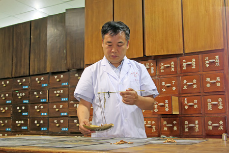 Luannan County - June 18th: a pharmacist weighing Chinese medicinal herbs, June 18th, 2015, Luannan County, Hebei Province, Chinaのeditorial素材