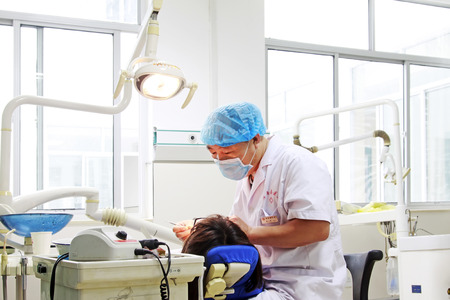 Luannan - June 29: doctor doing oral disease diagnosis and treatment, on June 29, 2015, luannan county, hebei province, Chinaのeditorial素材