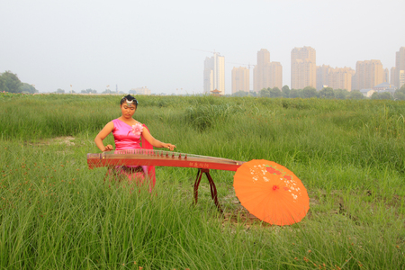 Luannan - August 8: girl playing guzheng in the park, August 8, 2015, luannan county, hebei province, Chinaのeditorial素材