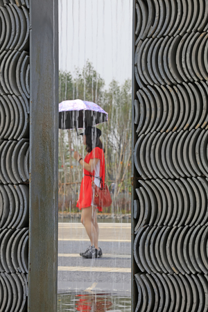 Tangshan City - June 10, 2016: lady with a red dress with an umbrella in the rain, in the park, Tangshan City, Hebei, China

のeditorial素材