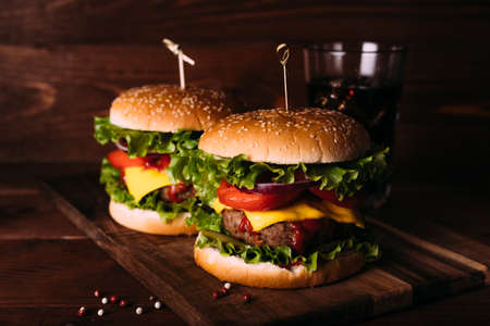 Two home made fresh tasty burgers with lettuce and cheese on wooden table.の写真素材
