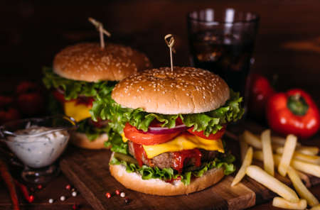 Two home made fresh tasty burgers with lettuce and cheese on wooden table.の写真素材