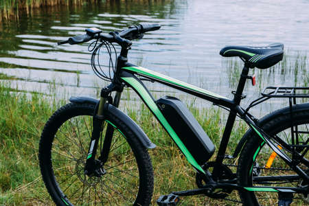 Electric bicycle in the park in summer day. The view of the e motor and power battery.