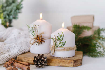 Christmas candles and fir branches on a white wooden background with lightsの写真素材