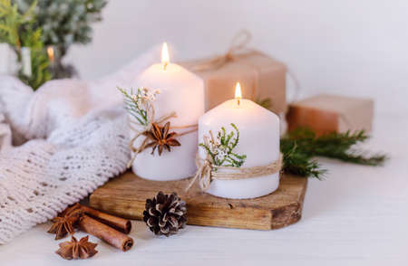 Christmas candles and fir branches on a white wooden background with lightsの写真素材
