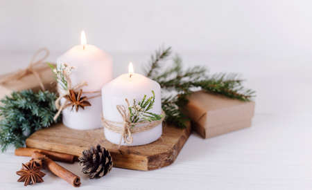 Christmas candles and fir branches on a white wooden background with lightsの写真素材